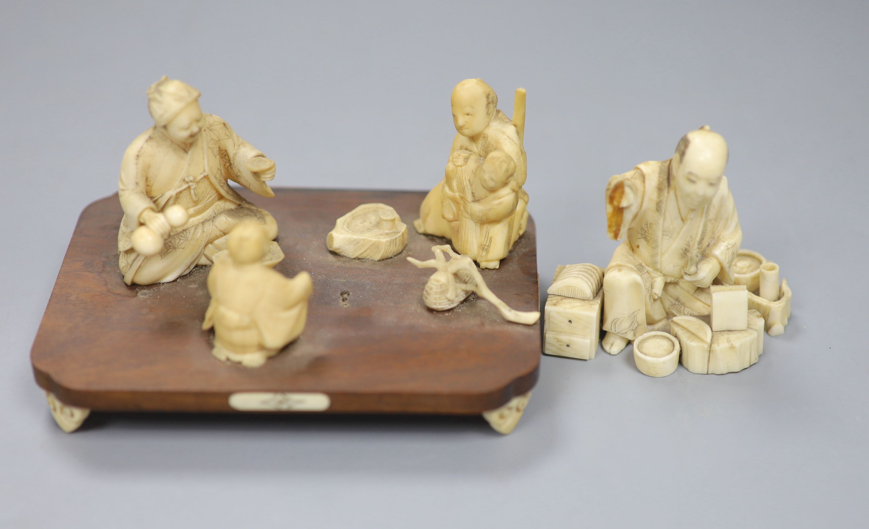 A Meiji period Japanese ivory okimono figural group, raised on a rosewood base and scrolled ivory feet, signed to underside 6cm high, 1